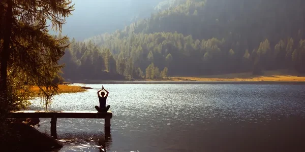 Person meditating by a serene mountain lake
